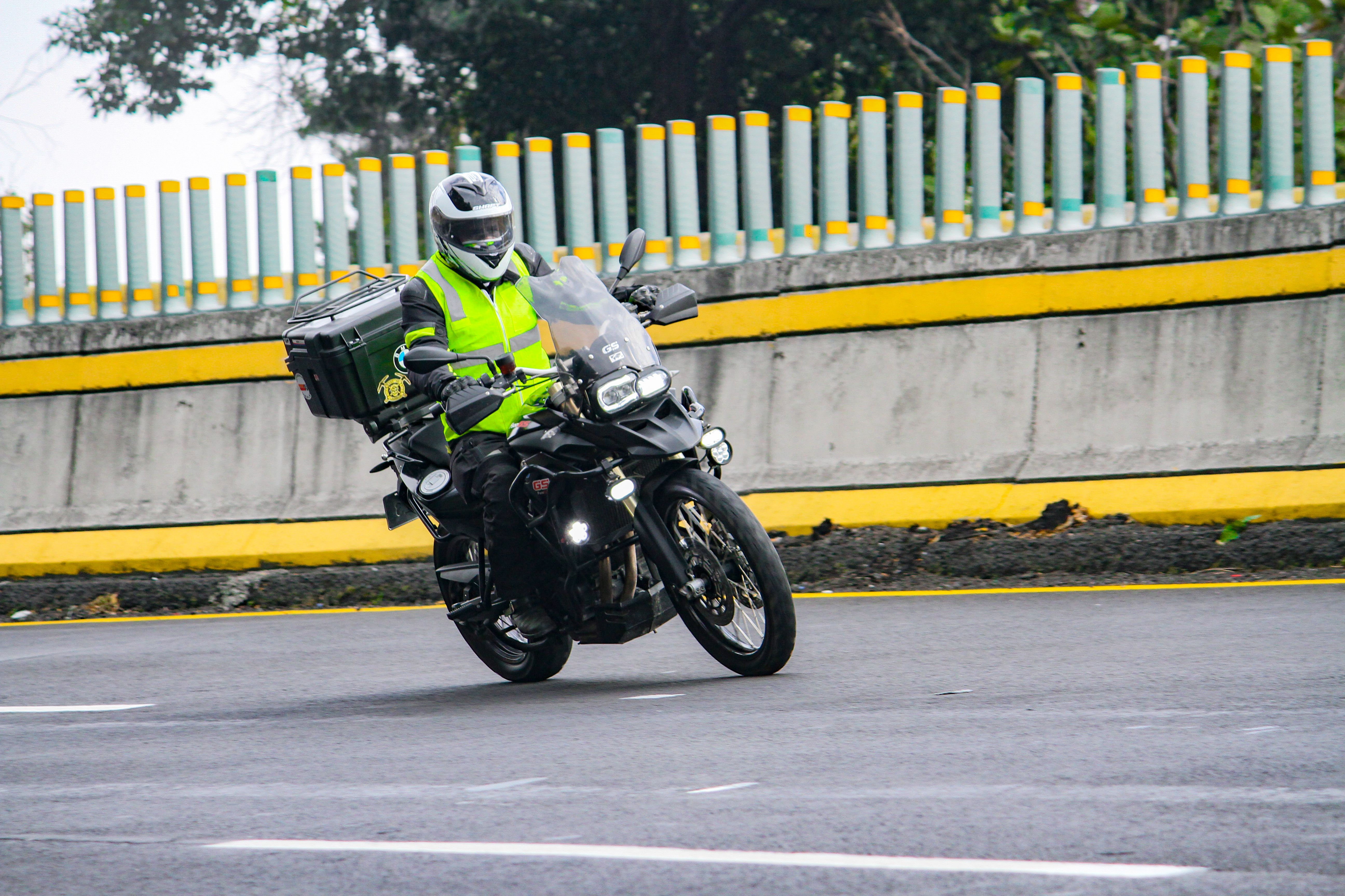 Motorcyclist wearing a high-visibility reflective vest leaning into a curve
