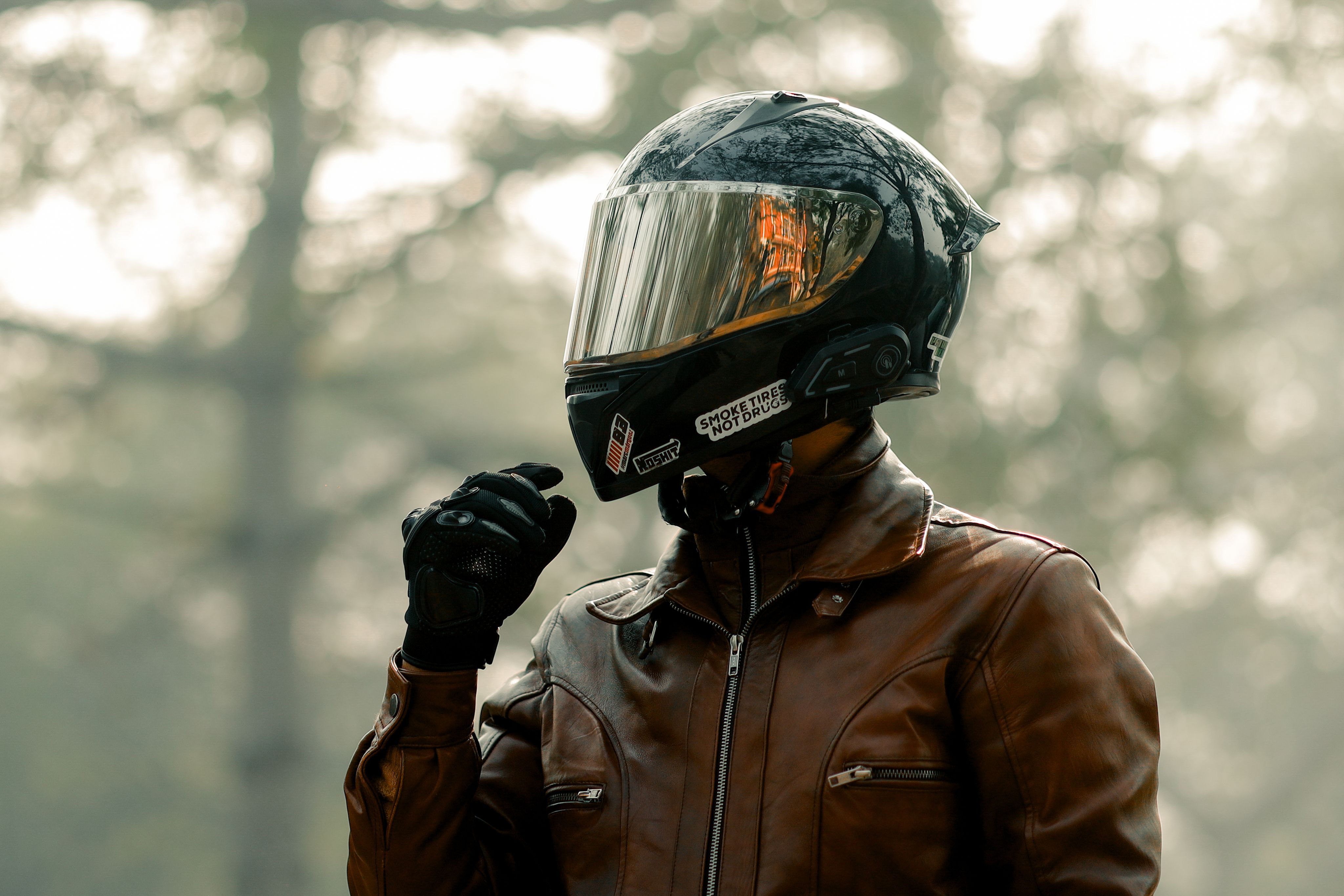 Biker in helmet and leather riding jacket in a foggy forest
