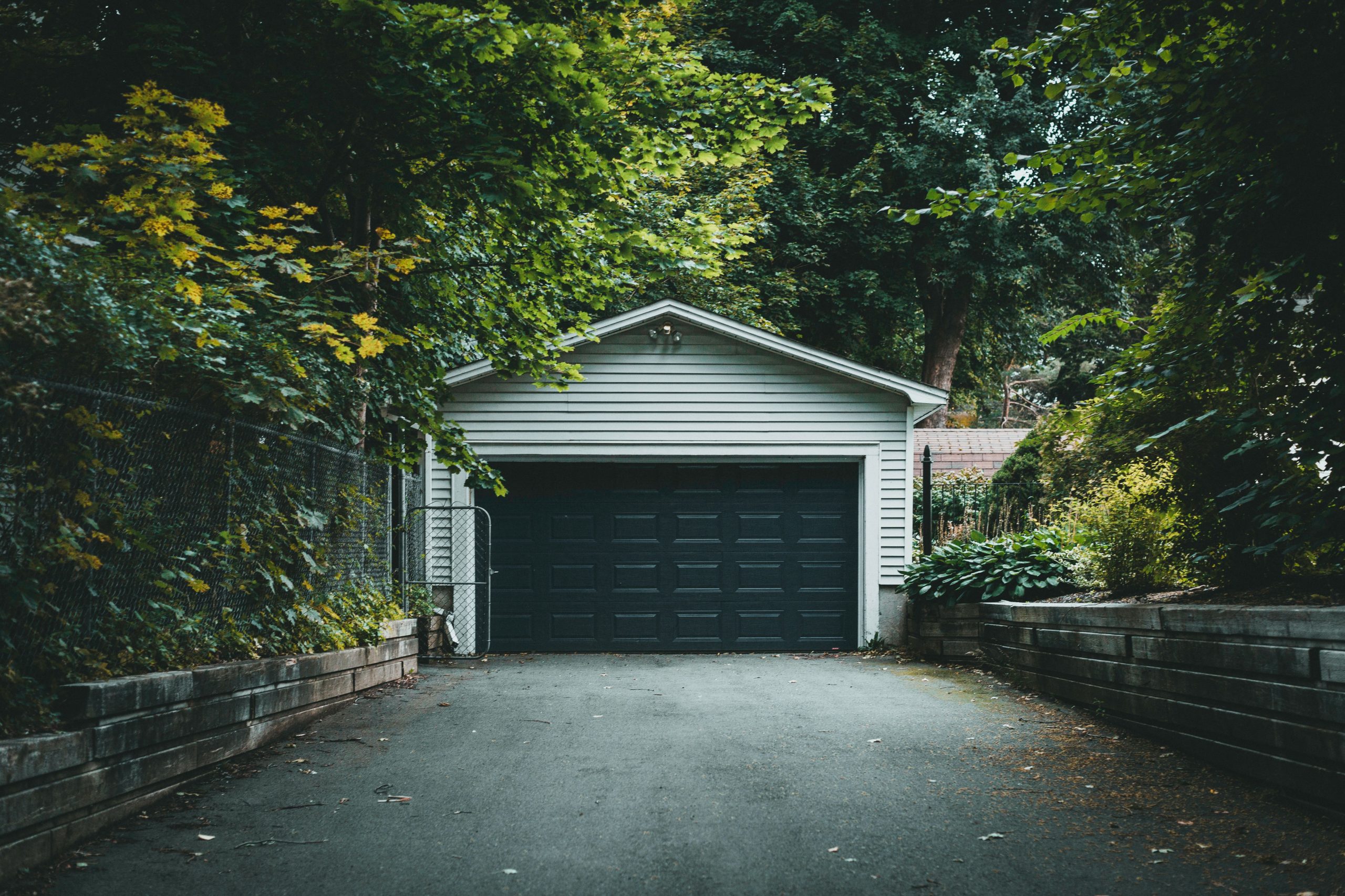 Residential garage and driveway screened by garden planting, illustrating how fencing can improve privacy around vehicle access.