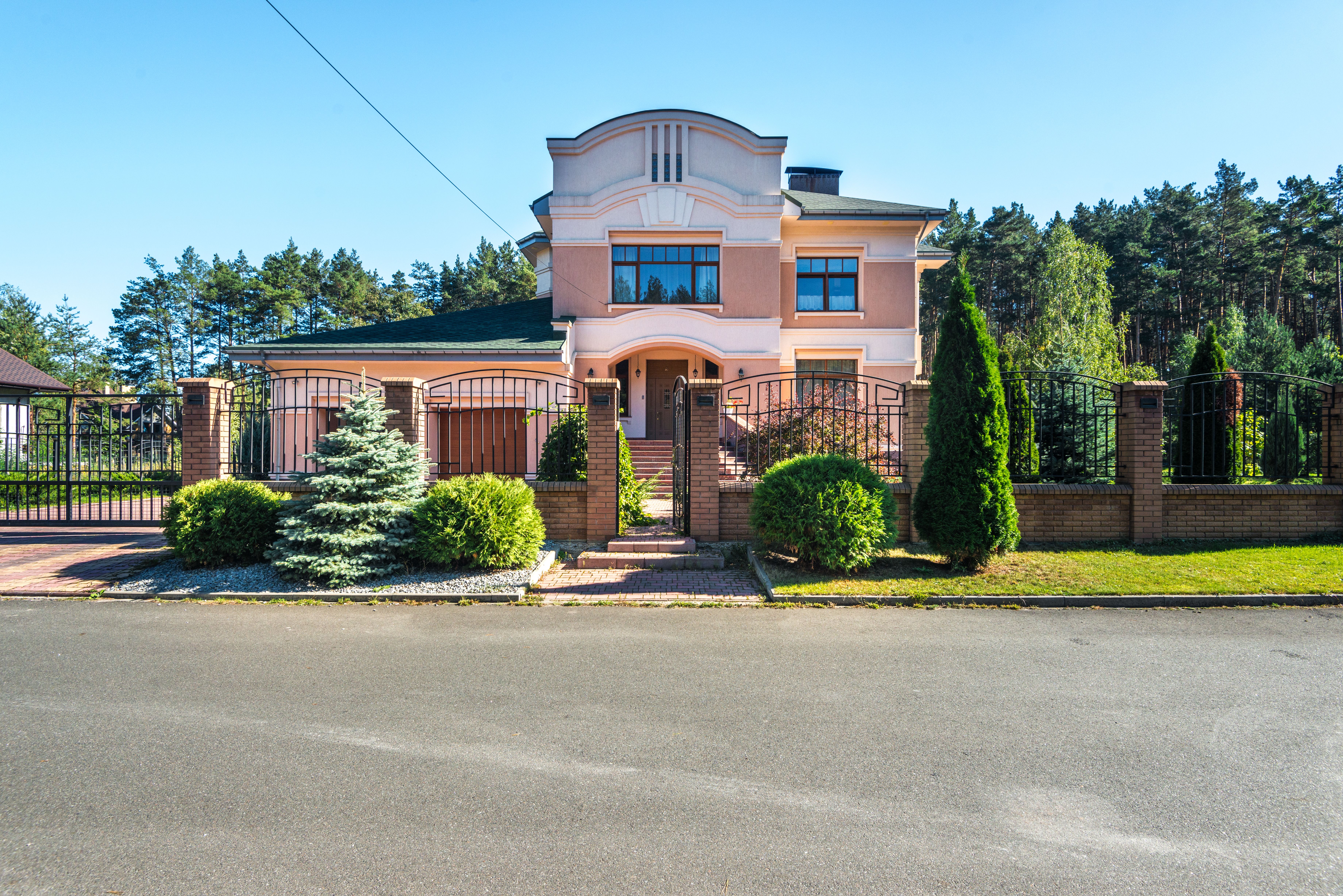 Modern suburban home with a gated entrance and landscaped frontage, showing a private driveway approach.