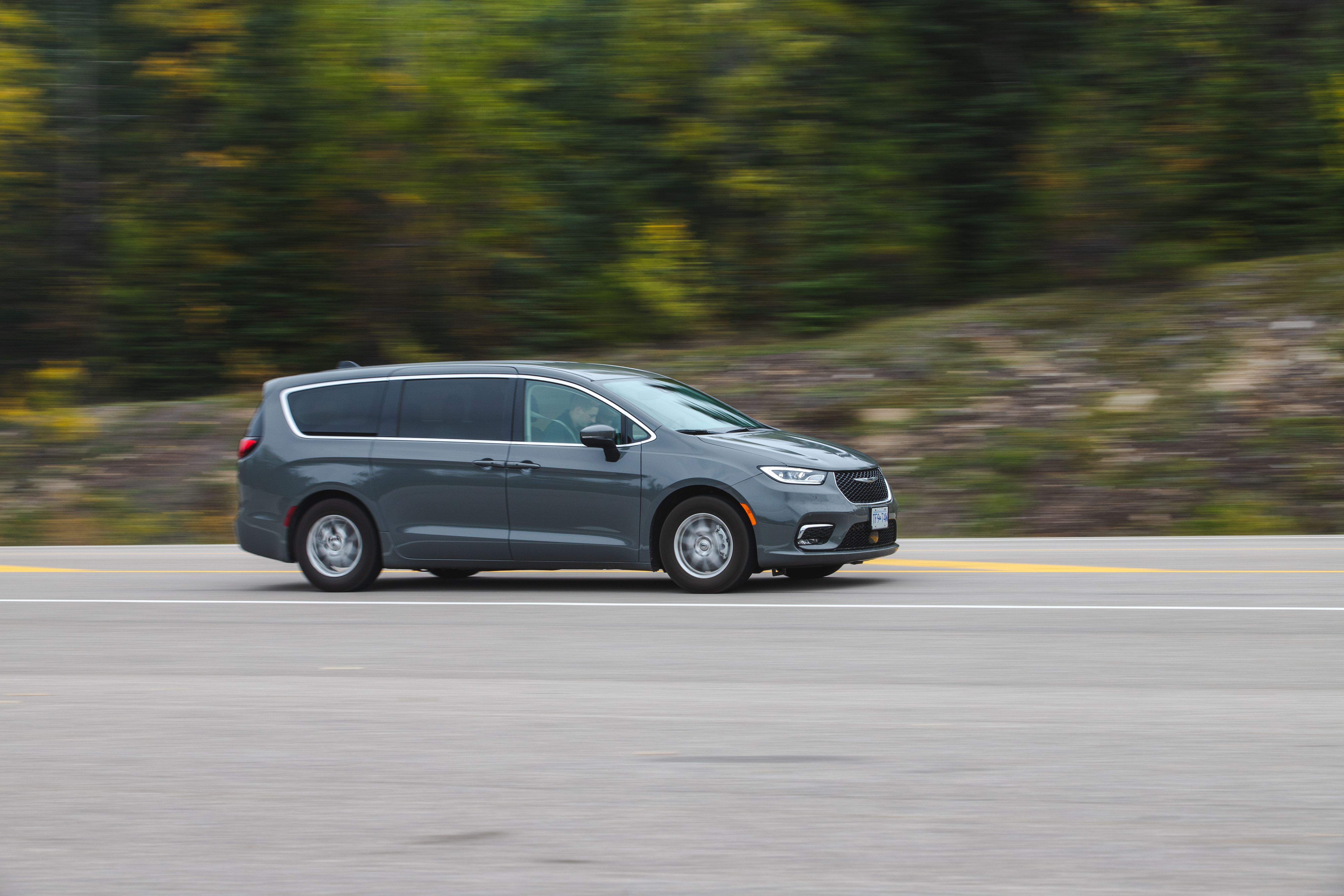 Modern minivan traveling along a green scenic highway, illustrating today's family road-trip vehicle.