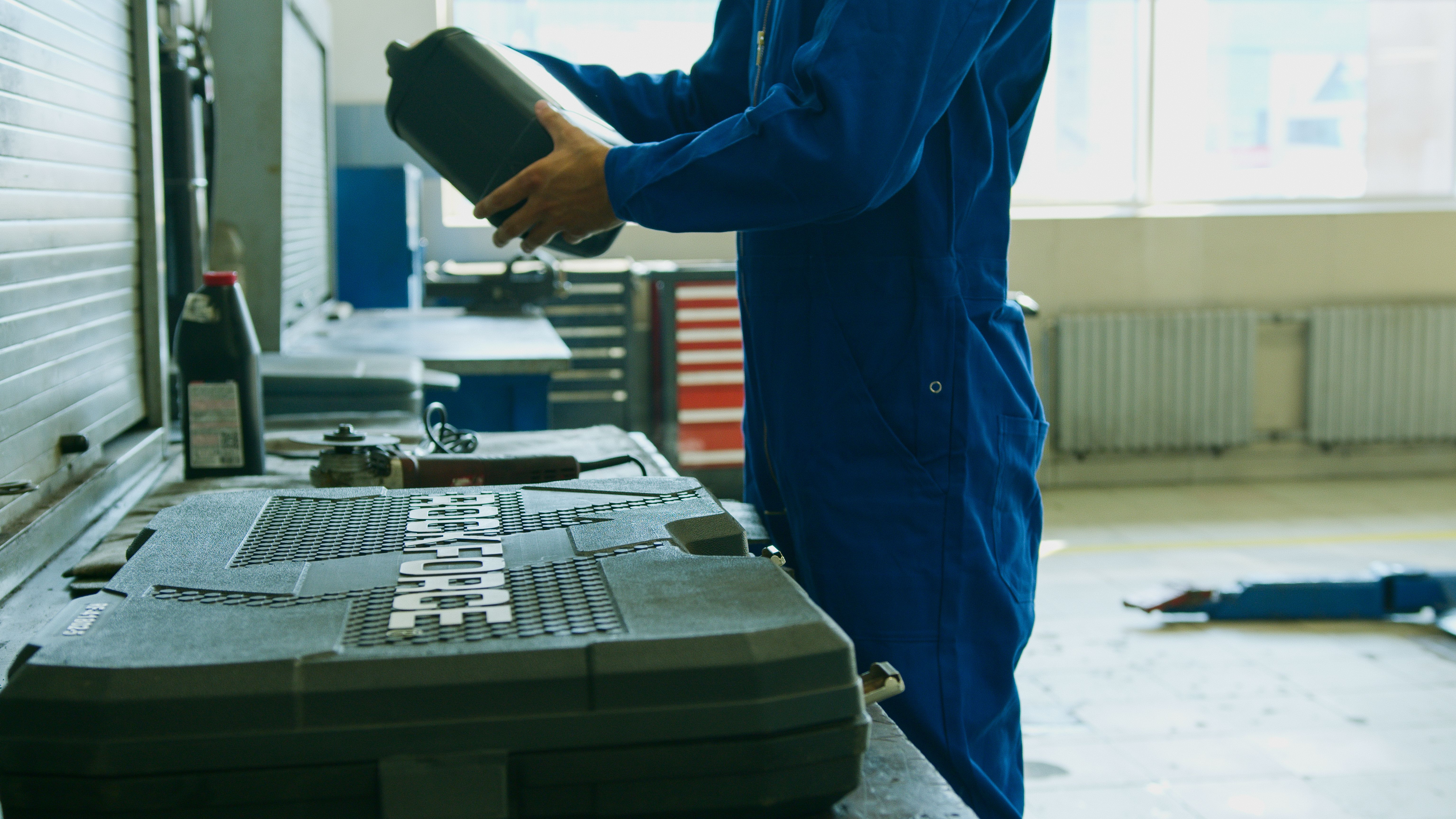 Mechanic holding an engine oil container inside an automotive workshop