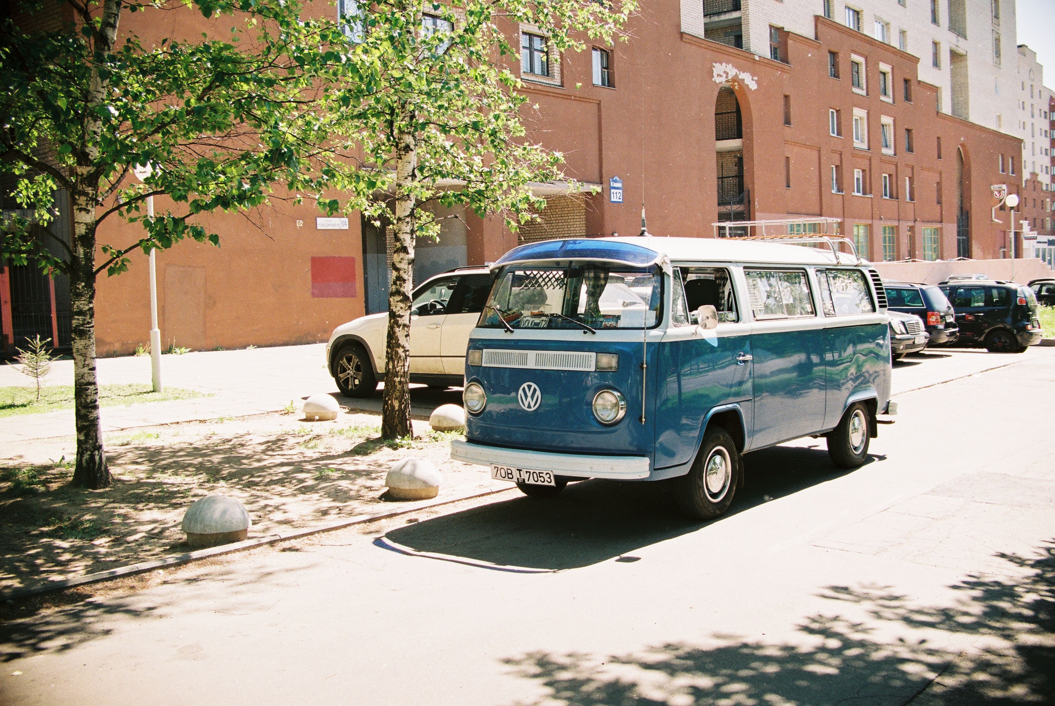 Classic blue Volkswagen Type 2 van parked on a sunny urban street, representing the postwar van era.